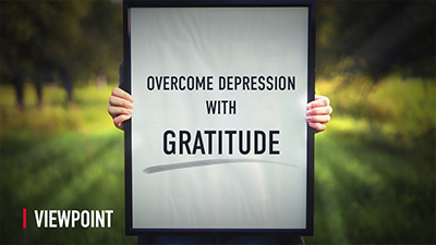 Someone holding a board on which it is written Overcome Depression with Gratitude